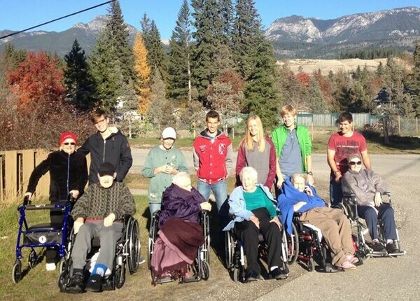 students posing with seniors in wheelchairs