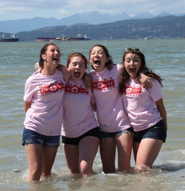 four students standing in ocean posing together